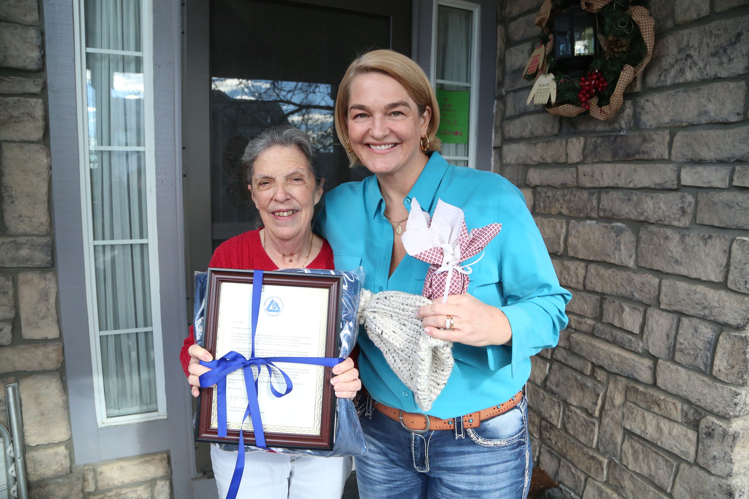City Manager stands with volunteer holding framed letter and smiling for the camera