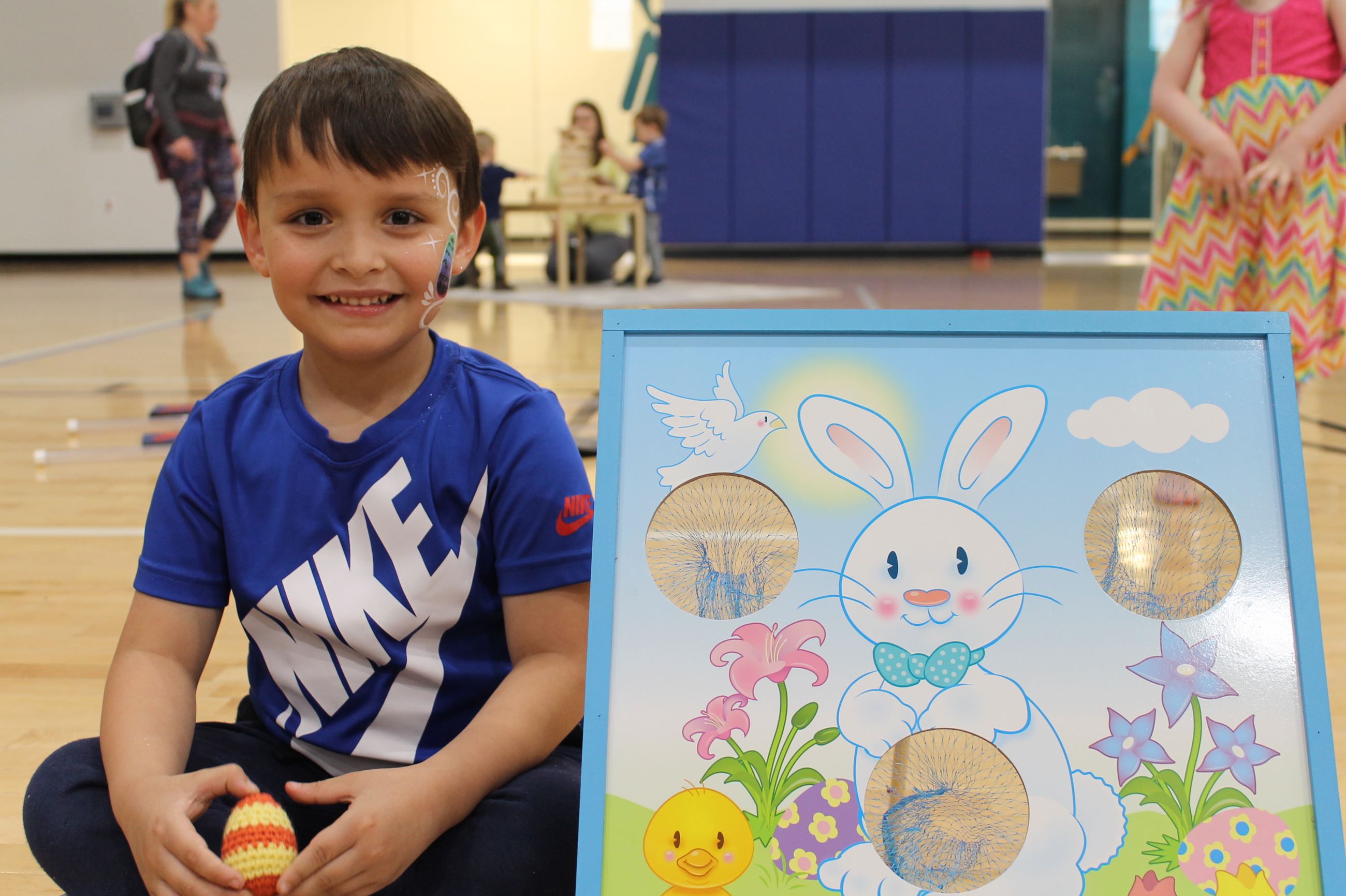 child sitting next to an easter game at the spring spectacular
