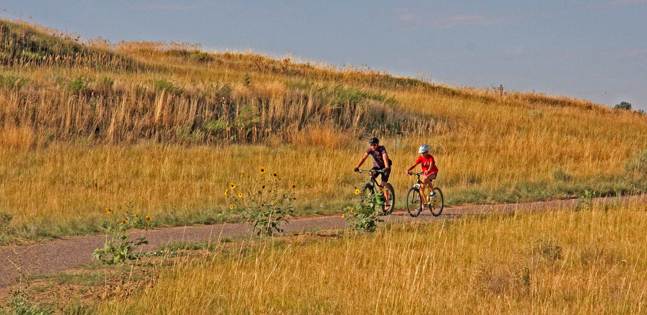 two people cycling on a trail in a field